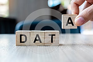 Businessman hand holding wooden cube block with DATA business word on table background. Database, Financial and marketing concepts