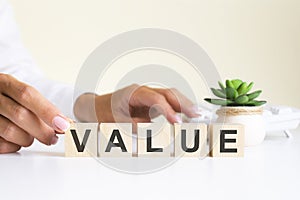 Businessman hand holding wooden cube block with Value business word on table background. Mission, Vision and core values