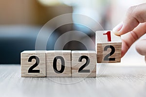 Businessman hand holding wooden cube with flip over block 2021 to 2022 text on table background. Resolution, strategy, solution,