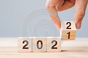 Businessman hand holding wooden cube with flip over block 2021 to 2022 text on table background. Resolution, strategy, solution,