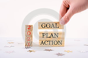 Businessman hand holding wooden cube with text 2021 GOAL, PLAN and ACTION on table background. Resolution, strategy, solution,