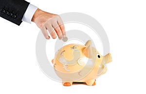A businessman hand inserting a coin into a piggy bank isolated, concept for business and save money