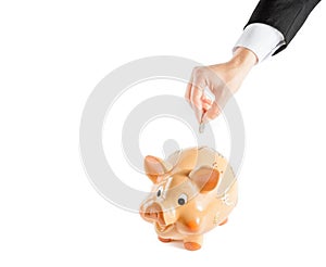 A businessman hand inserting a coin into a piggy bank isolated, concept for business and save money