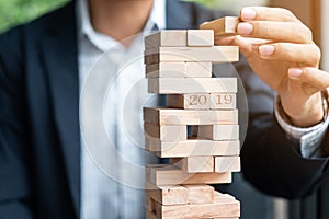 Businessman hand placing or pulling wooden block on the tower. Business planning, Risk Management