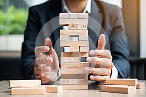 Businessman hand placing or pulling wooden block on the tower. Business planning, Risk Management