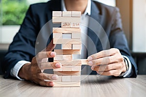 Businessman hand placing or pulling wooden block on the tower. Business planning, Risk Management