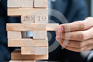 Businessman hand placing or pulling wooden block on the tower. Business planning, Risk Management