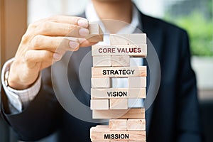 Businessman hand placing or pulling wooden block on the tower. Business planning, Risk Management, Solution, Mission, Vision, Core