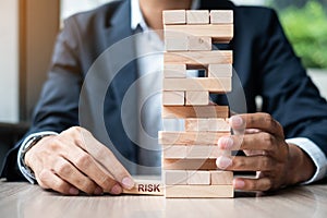 Businessman hand placing or pulling wooden block on the tower. Business planning, Risk Management, Solution and strategy Concepts