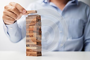 Businessman hand placing or pulling wooden block on the tower. Business planning, Risk Management, Solution and strategy Concepts