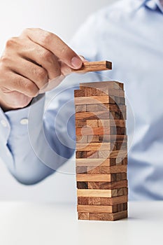 Businessman hand placing or pulling wooden block on the tower. Business planning, Risk Management, Solution and strategy Concepts