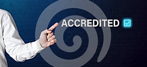 Businessman hand points to the word accredited