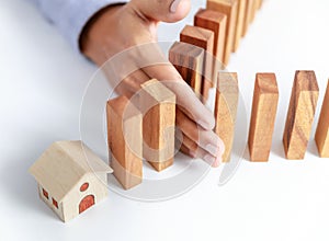 Businessman hand protect wooden home toy block from danger and fall