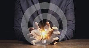 Businessman hand protecting with lightbulb with virtual brain glowing , patent and creative idea innovation concept