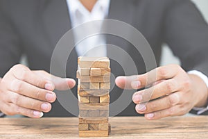 Businessman hand put wood blocks. Investment risk and uncertainty in the real estate housing market. Property investment