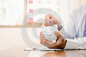 Businessman hand putting coin into blue piggy bank, saving money for future investment plan and retirement fund concept