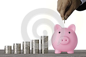 Businessman hand putting coin into piggy bank with saving growth on stacking coin growing  and white background, meaning