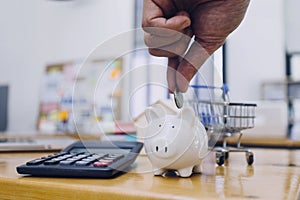 businessman hand putting coin in piggy bank. Saving money concept, business finance and investment