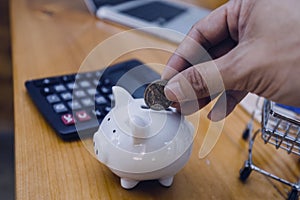 businessman hand putting coin in piggy bank. Saving money concept, business finance and investment