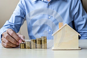 Businessman hand putting golden coin on growing money stairs or stack with house model. business, investment, retirement planning