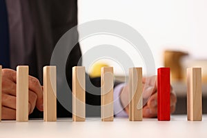 Businessman hand selects red wooden block on table