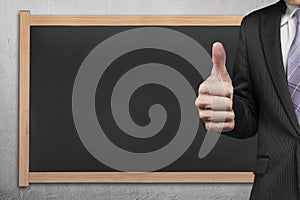 Businessman hand showing thumb up with blank blackboard