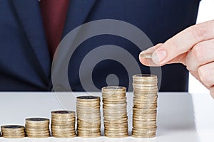 Businessman hand stacking one euro coins into increasing columns