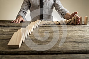 Businessman hand stopping domino effect photo