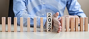 Businessman hand Stopping Falling of 2022 wooden Blocks. Business, Risk Management, Insurance, Resolution, strategy, solution,