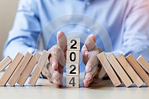 Businessman hand Stopping Falling of 2024 wooden Blocks. Business, Risk Management, Insurance, Resolution, strategy, solution,