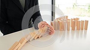 Businessman hand Stopping Falling wooden Blocks