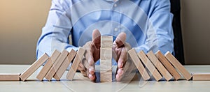 Businessman hand Stopping Falling wooden Blocks or Dominoes. Business, Risk Management, Solution, Insurance and strategy Concepts