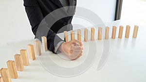 Businessman hand strongly stop dominoes continuous toppled