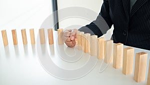 Businessman hand strongly stop dominoes continuous toppled