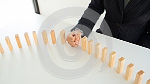 Businessman hand strongly stop dominoes continuous toppled