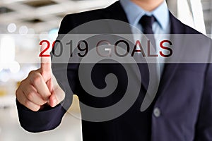 Businessman hand touching 2019 goals button over blur office background, banner with copy space, annual plan for success in