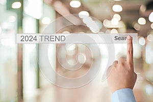 Businessman hand touching 2024 trends search bar over blur office background, banner, SEO 2024 business trends planning, success