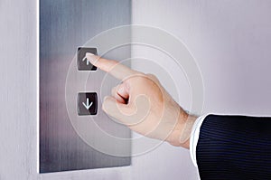 Businessman hand touching going up sign on lift control panel