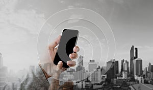 Businessman hand using mobile smart phone with double exposure modern city background, blank black screen