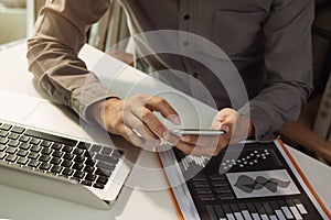 Businessman hand using smartphone, mobile p payments online shopping, omni channel, and analyzing graph document.