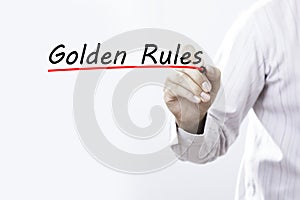 Businessman hand writing Golden Rules with red marker on transparent wipe board, business concept