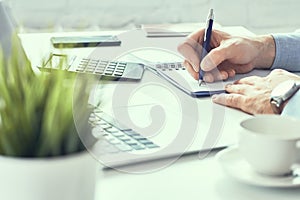 Businessman hand writing note on a notebook. Business man working at office desk. Close up of empty notebook on a