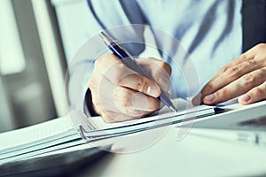 Businessman hand writing note on a notebook. Business man working at office desk. Close up of empty notebook on a