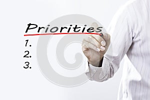 Businessman hand writing Priorities with red marker on transparent wipe board, business concept photo