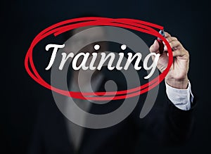 Businessman hand writing `Training` with red marker on transparent board.