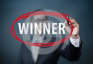 Businessman hand writing `Winner` with red marker on transparent board.