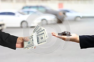 Businessman handed the money to Businesswoman or saleswoman holding miniature car model, auto business, car trading, loans for car