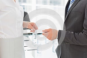 Businessman handing businesswoman a card