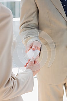 Businessman handing card to businesswoman