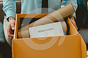 Businessman hands carrying a brown cardboard box to resignation